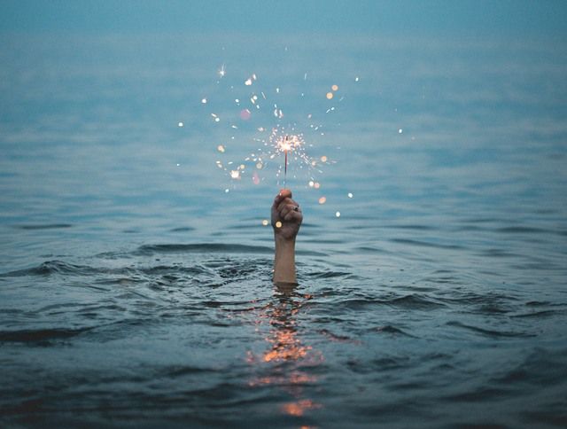 A Person Showing Life Holding A Firework From The Water