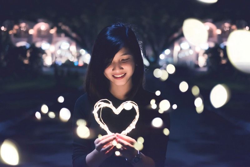 an impressed girl holding a heart shaped light